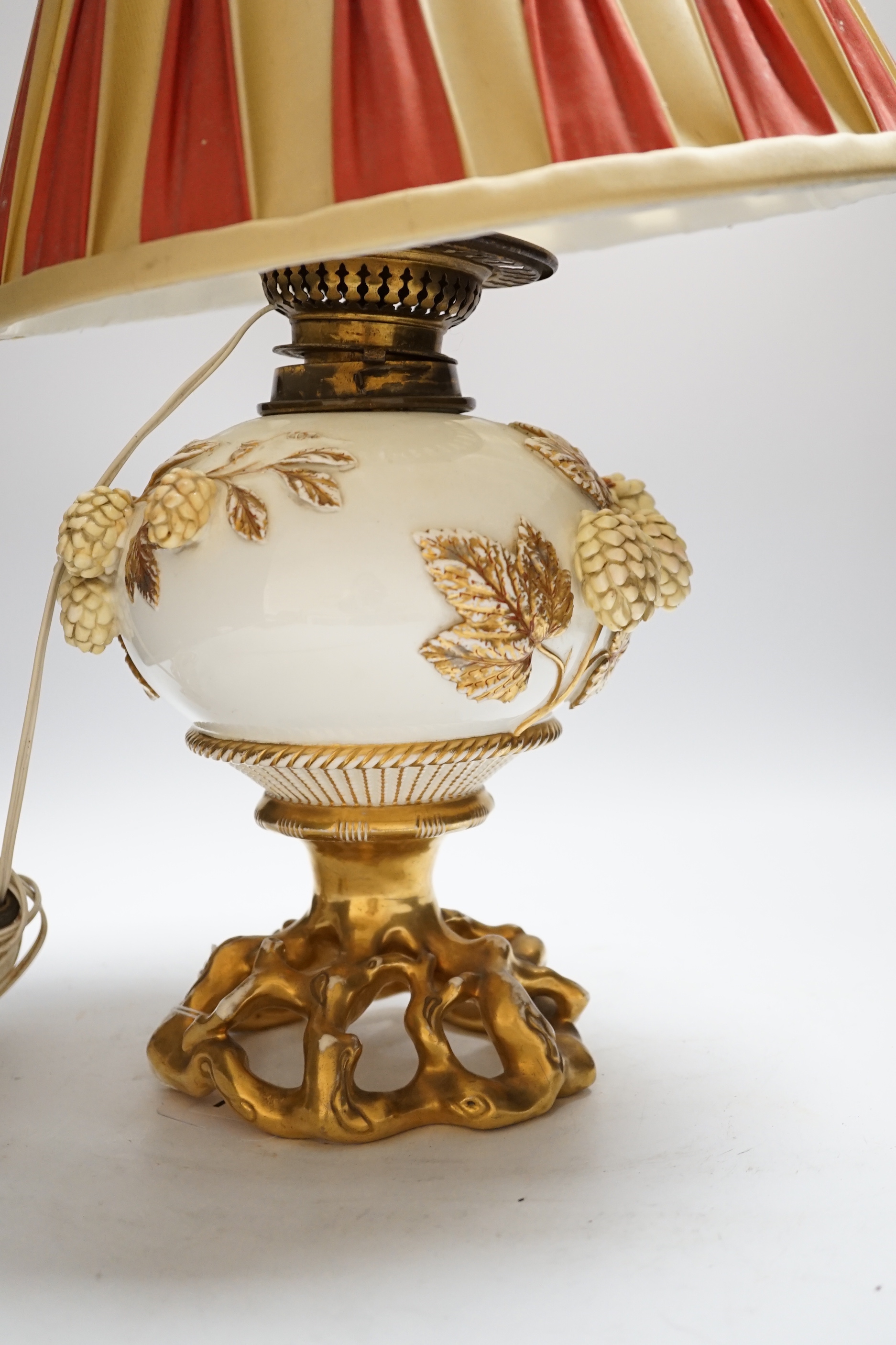 A Victorian porcelain oil lamp, probably Moore brothers, decorated with hops and gilt base, converted to electric, 45cm high